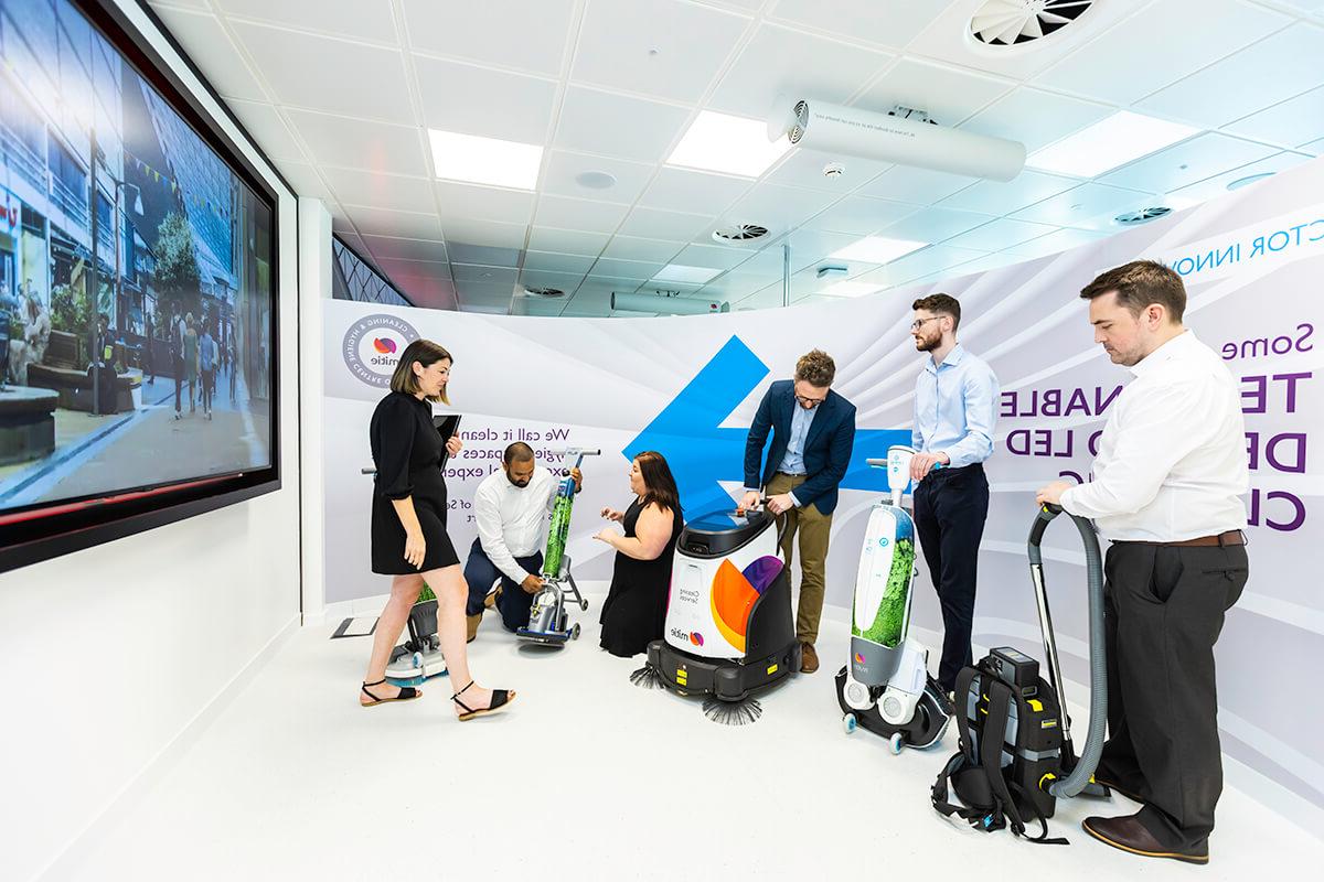 Various people trying out different cleaning robots and technology at the Mitie Cleaning and Hygiene Centre of Excellence