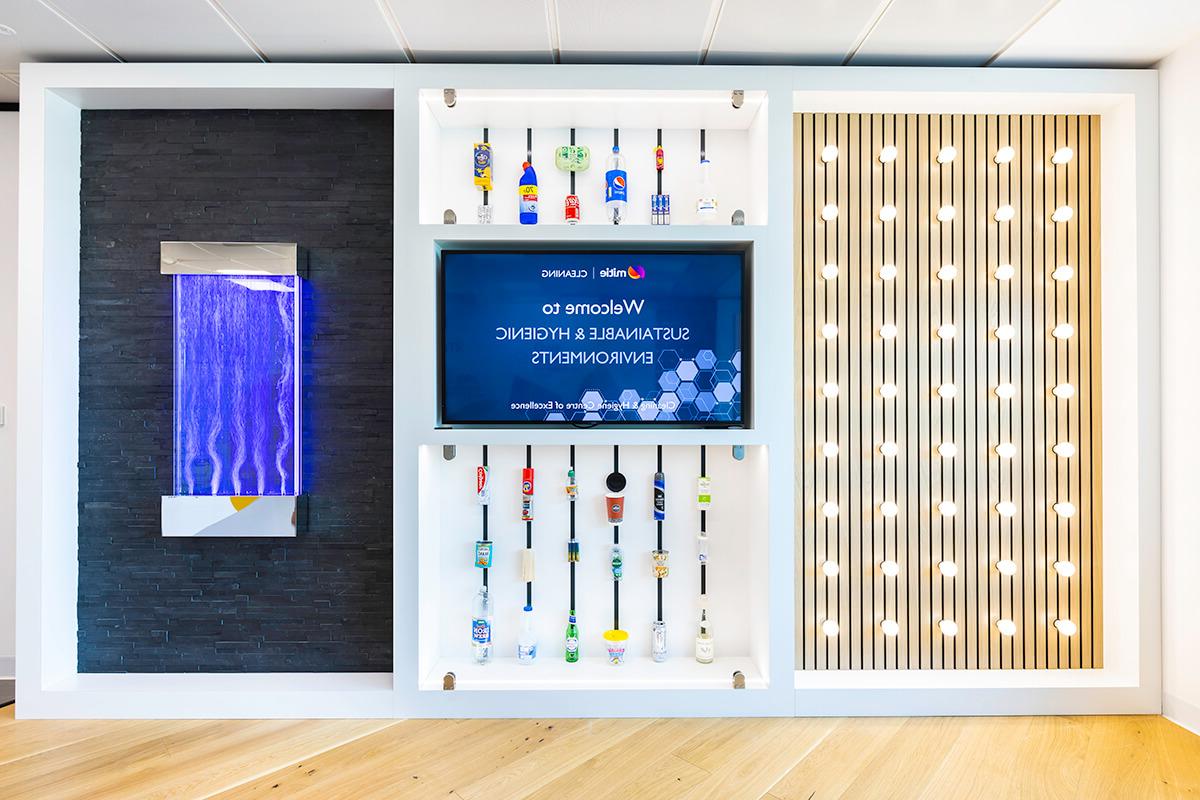 A wall displaying various empty containers for household products, lights, water jets and a flat-screen TV. Part of the Mitie Cleaning and Hygiene Centre of Excellence